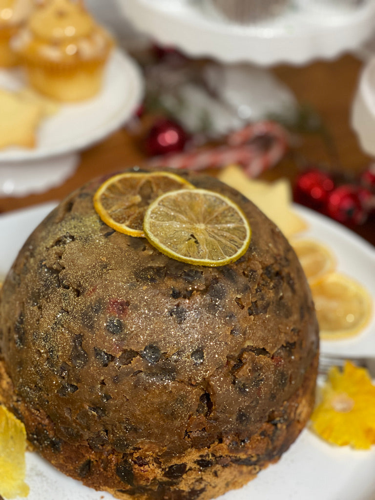 Christmas pudding with candied citrus slices on a white plate
