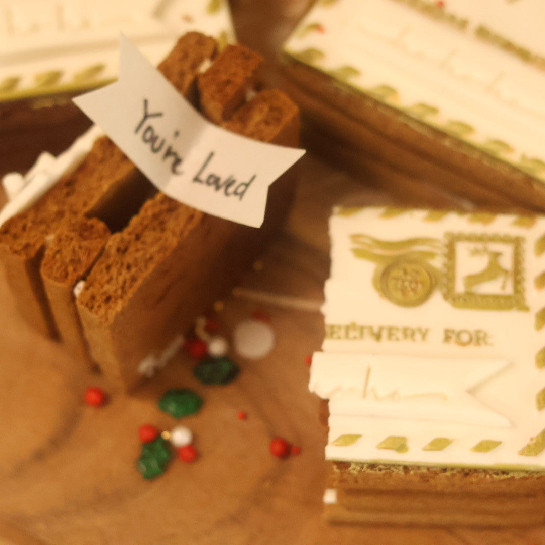 Gingerbread house with a 'You're Loved' sign on a wooden surface