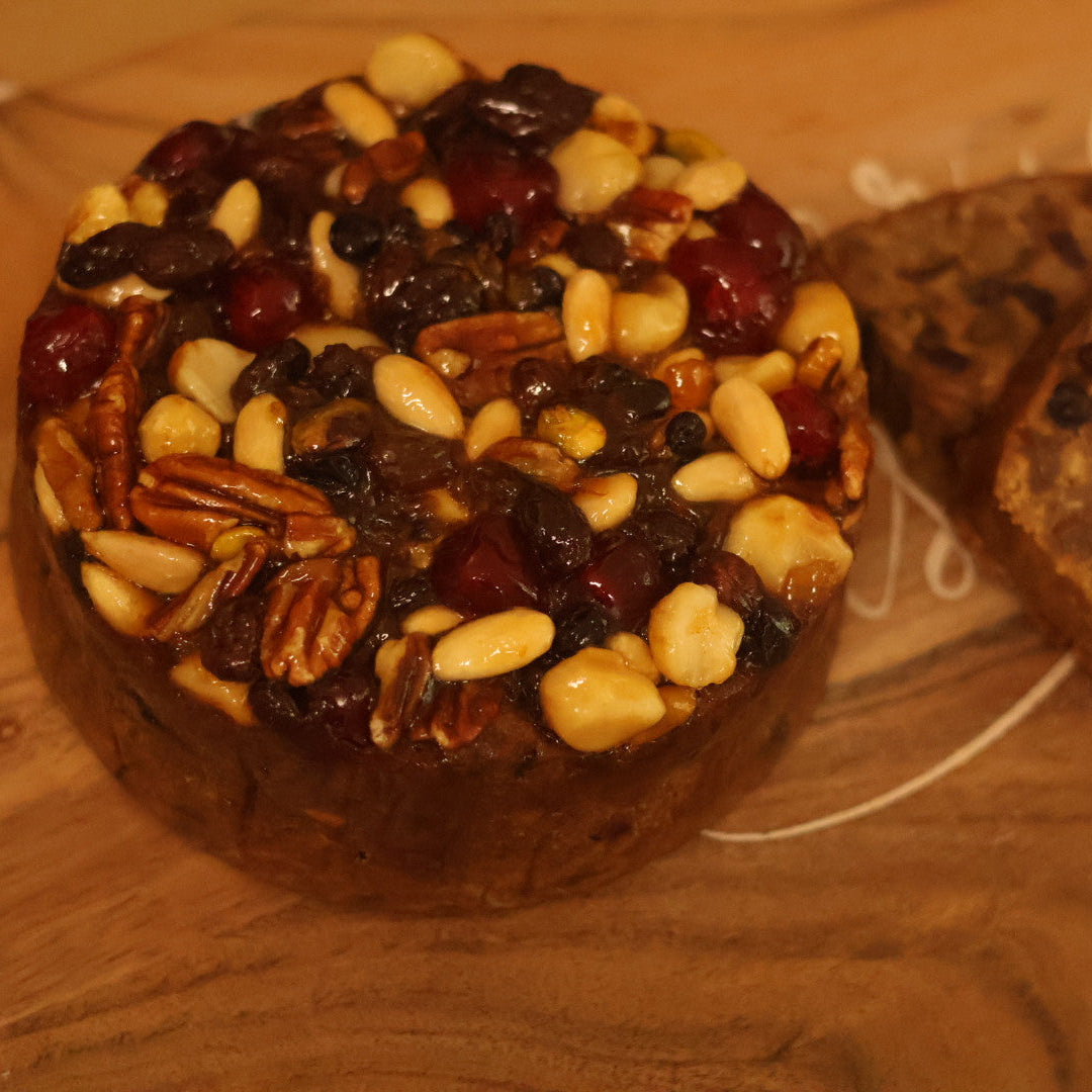 Two round fruitcakes with nuts and dried fruits on a wooden surface