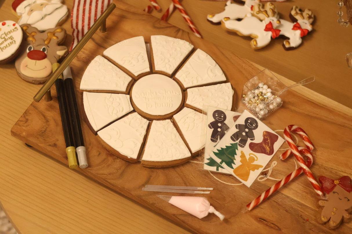 Decorative cookie cutter set on a wooden surface with Christmas-themed items.