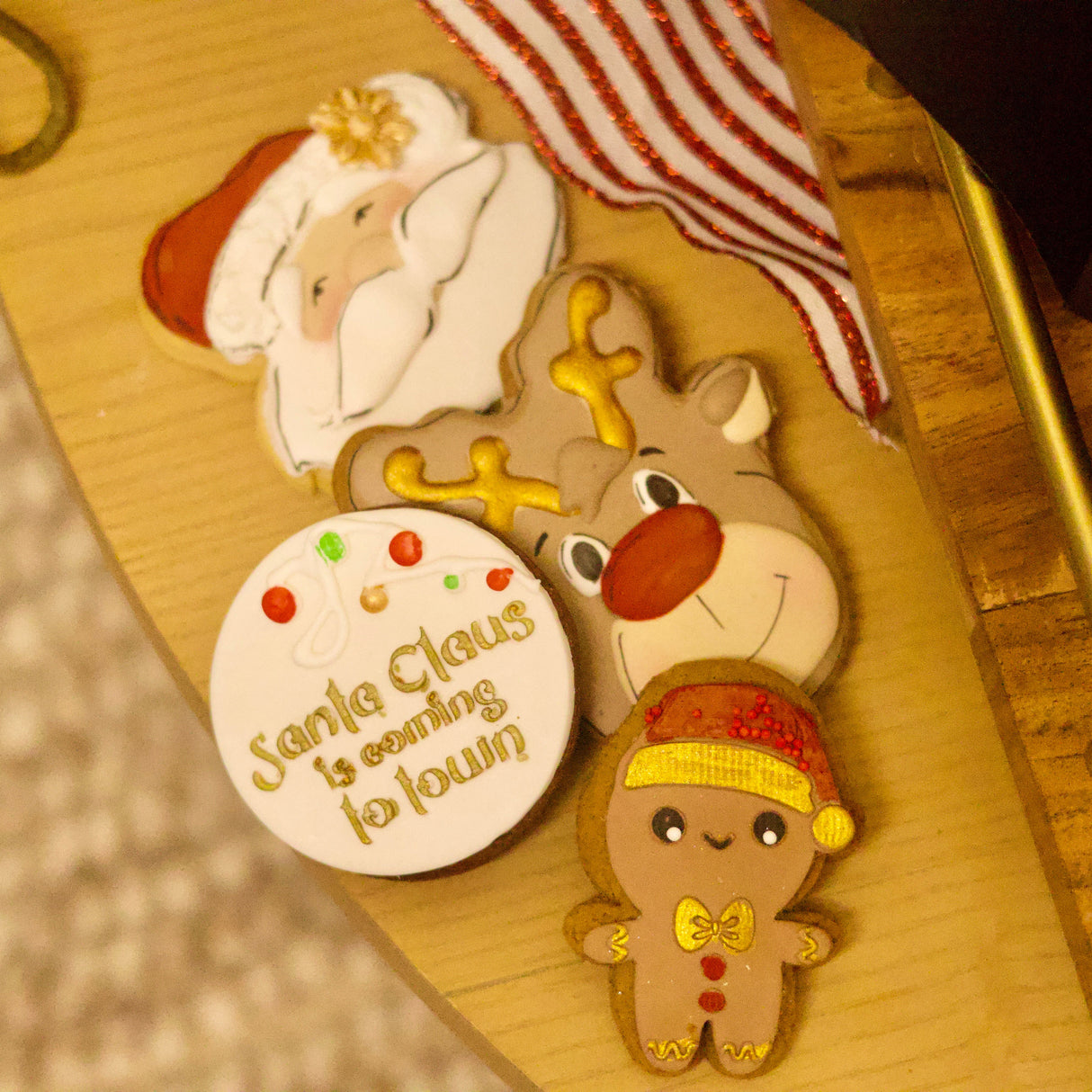 Decorative Christmas cookies shaped like Santa Claus, a reindeer, and a gingerbread man on a wooden surface.