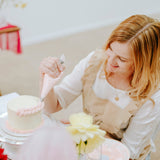 Woman decorating a cake with a piping bag in a casual setting