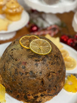 Christmas pudding with candied citrus slices on a white plate