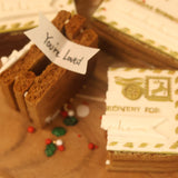Gingerbread house with a 'You're Loved' sign on a wooden surface