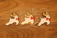 Three reindeer-shaped cookies with red bows on a wooden surface with 'Merry Christmas' text.