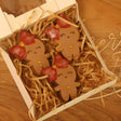 Decorative gingerbread cookies in a box with festive straw on a wooden surface.