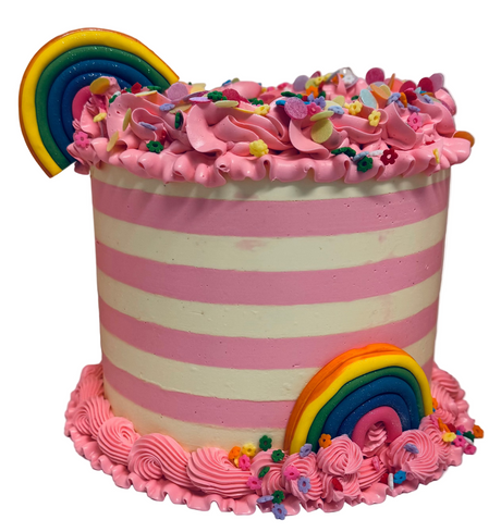 Colorful striped cake with pink frosting, rainbow decorations, and candy on a white background